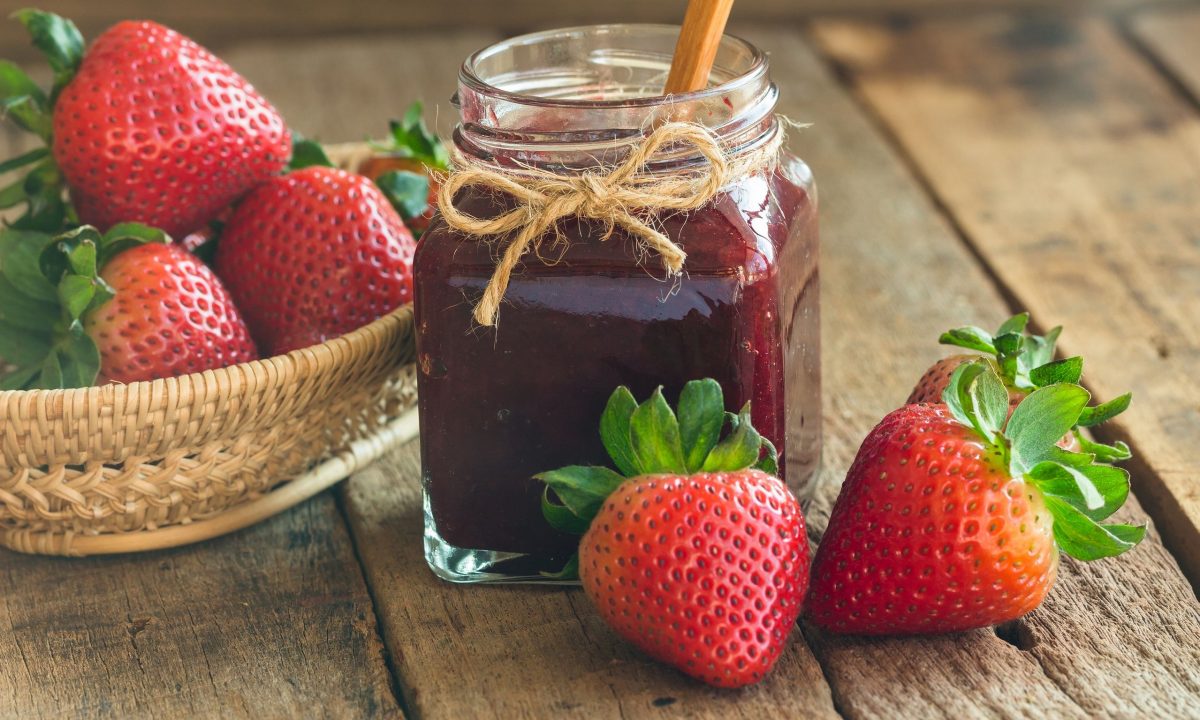 Μαρμελάδα φράουλα με μια κούπα καστανή ζάχαρη