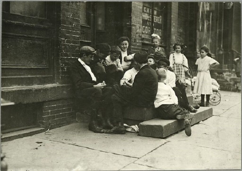 Παιδιά πλούσιων οικογενειών παίζουν κάρτες έξω από ένα εργοστάσιο όπου μέσα εργάζονται άλλα παιδιά