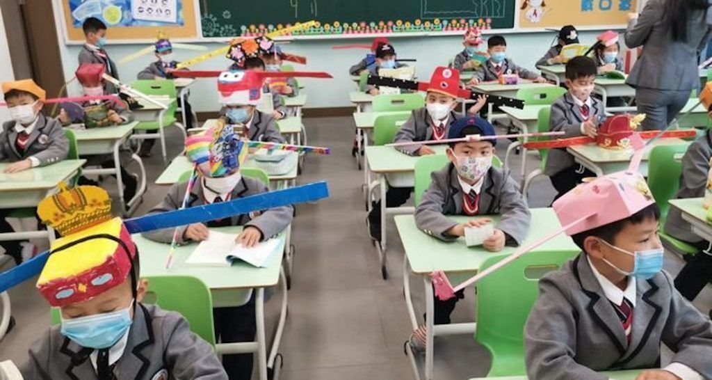 Παιδιά στη Χανγκτσόου φορούν καπέλα κοινωνικής αποστασιοποίησης με το που επιστρέφουν στο σχολείο