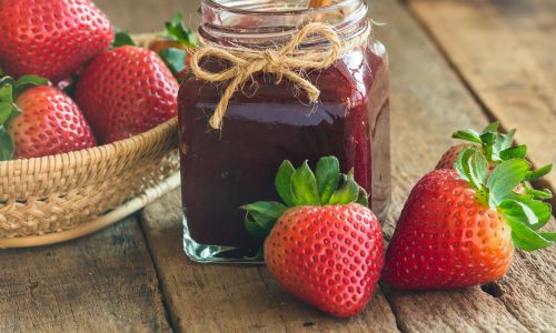 Μαρμελάδα φράουλα με μια κούπα καστανή ζάχαρη