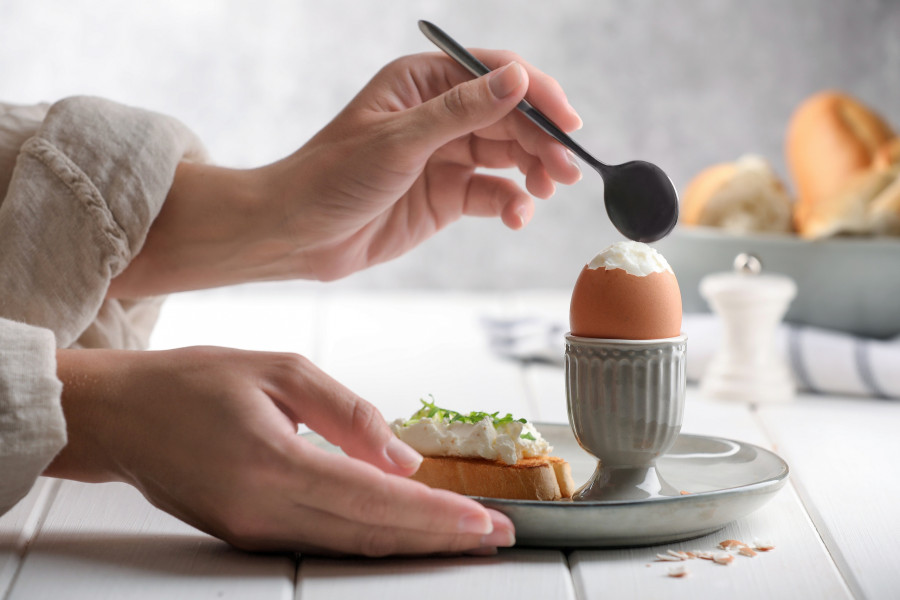 Woman Eating Fresh Soft Boiled Egg At White Wooden Table, Closeup
