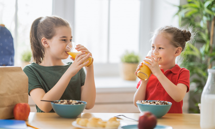 Happy children having breakfast. Kids eating cereal in kitchen.